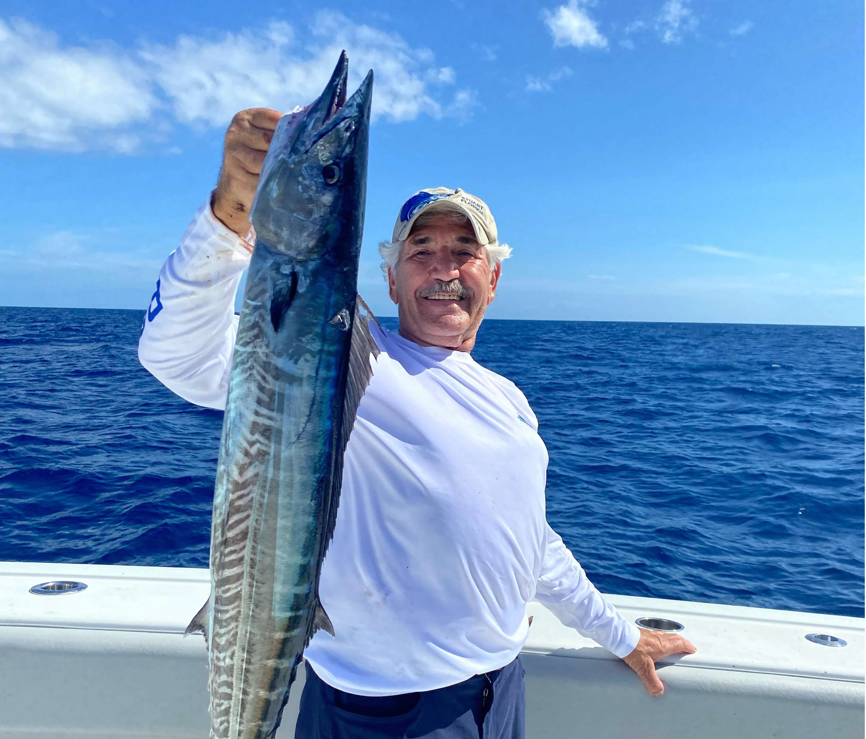 Fisherman holding wahoo fish on Next Level sport Fishing boat in ocean on sunny day