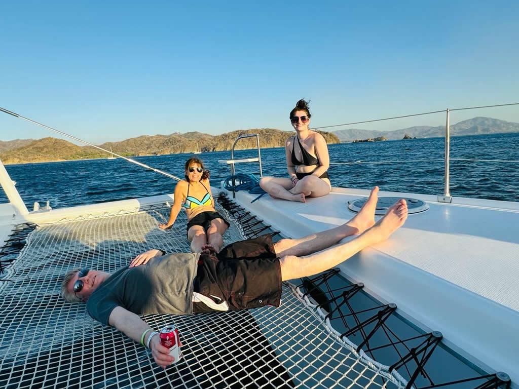 People enjoying leisure time and vacations sitting on the deck of the "Why Not" Catamaran Tour Papagayo.